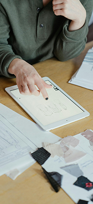 Person in Gray Sweater Holding White Tablet Computer